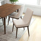 Modern wood dining table with beige upholstered chairs in a bright, contemporary home setting