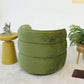 Modern green velvet accent chair with round side table and decorative plant in living room
