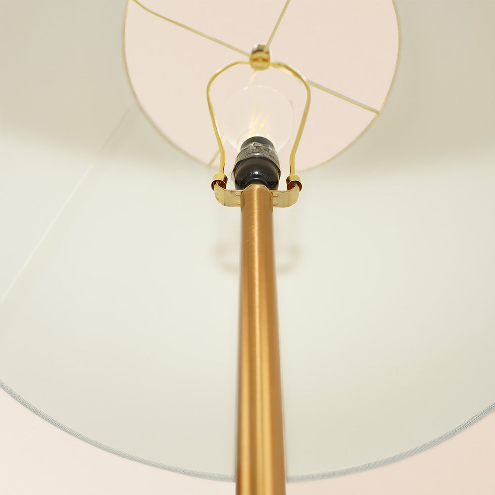 Close-up of modern gold floor lamp with white lampshade from FredCo International furniture