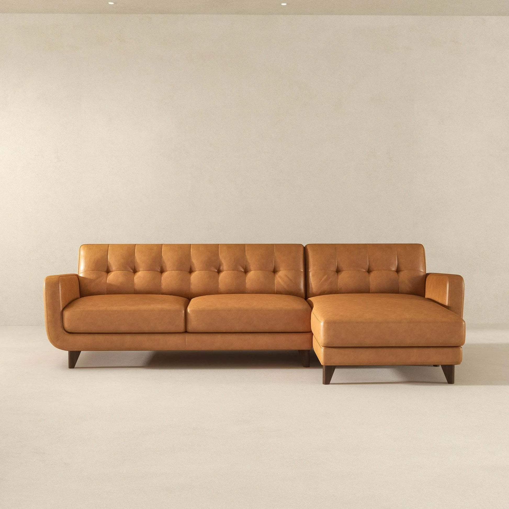 Mid-century modern tan leather sectional sofa with tufted back, displayed in a minimal room