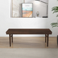 Modern wood slat bench in a minimalist living room with art, books, and a plant