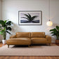 Modern living room with brown leather sectional sofa, indoor plants, and framed wall art