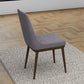 Modern gray upholstered dining chair with wooden legs on a textured rug in a stylish home setting