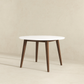Modern round dining table with white top and wooden legs on neutral background