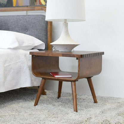 Mid-century modern wooden nightstand with lamp and book beside a bed in stylish bedroom
