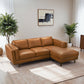 Modern tan leather sectional sofa in bright living room with plants and abstract wall art