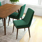 Modern green dining chairs with wooden legs around a wood table in a bright home setting