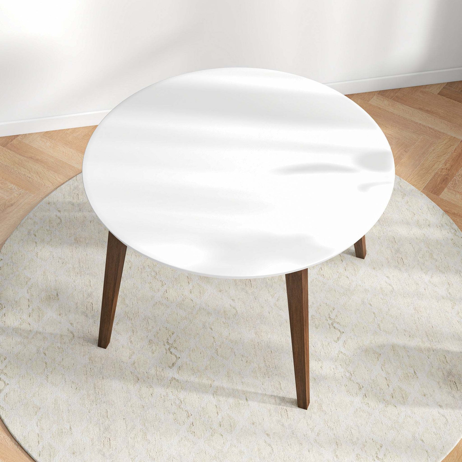Modern round white coffee table with wooden legs on a light rug, hardwood floor, FredCo International