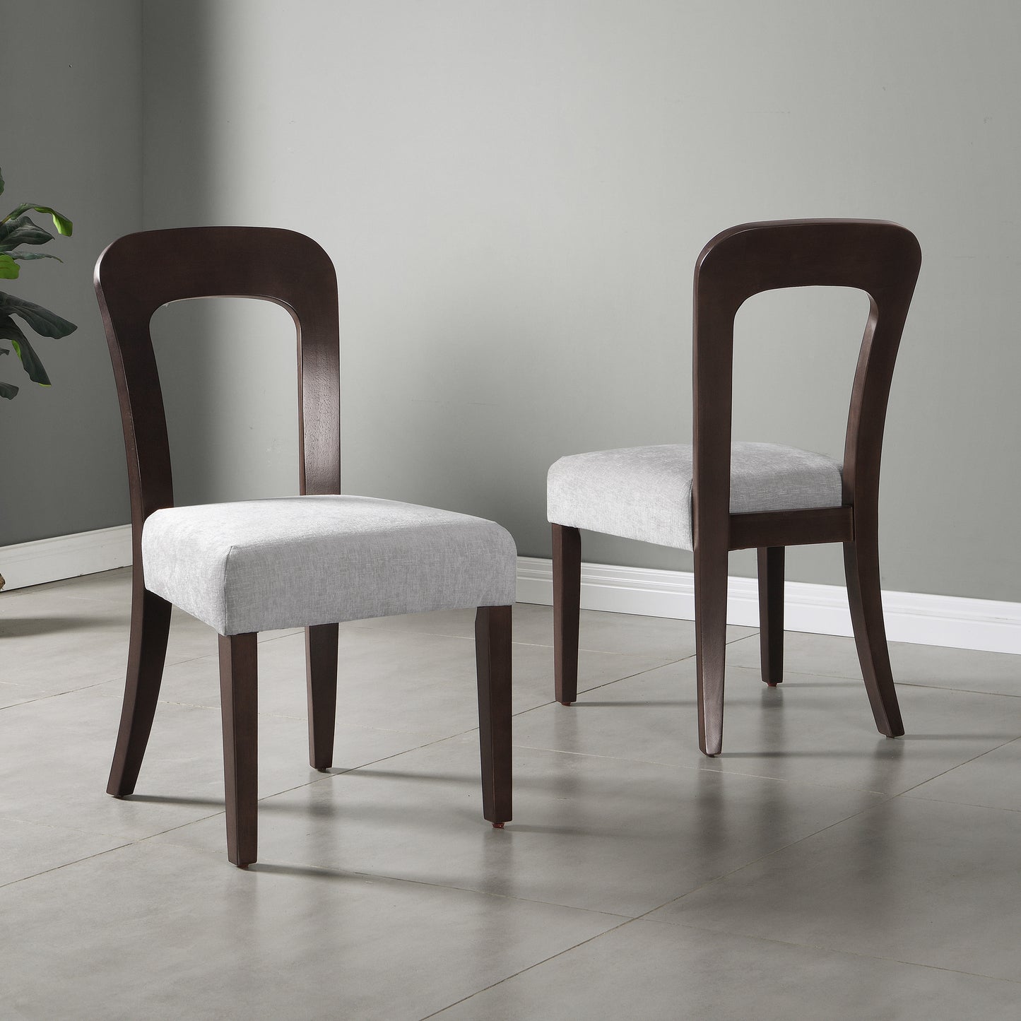 Modern dining chairs with dark wood frames and light gray upholstered seats in a minimal room