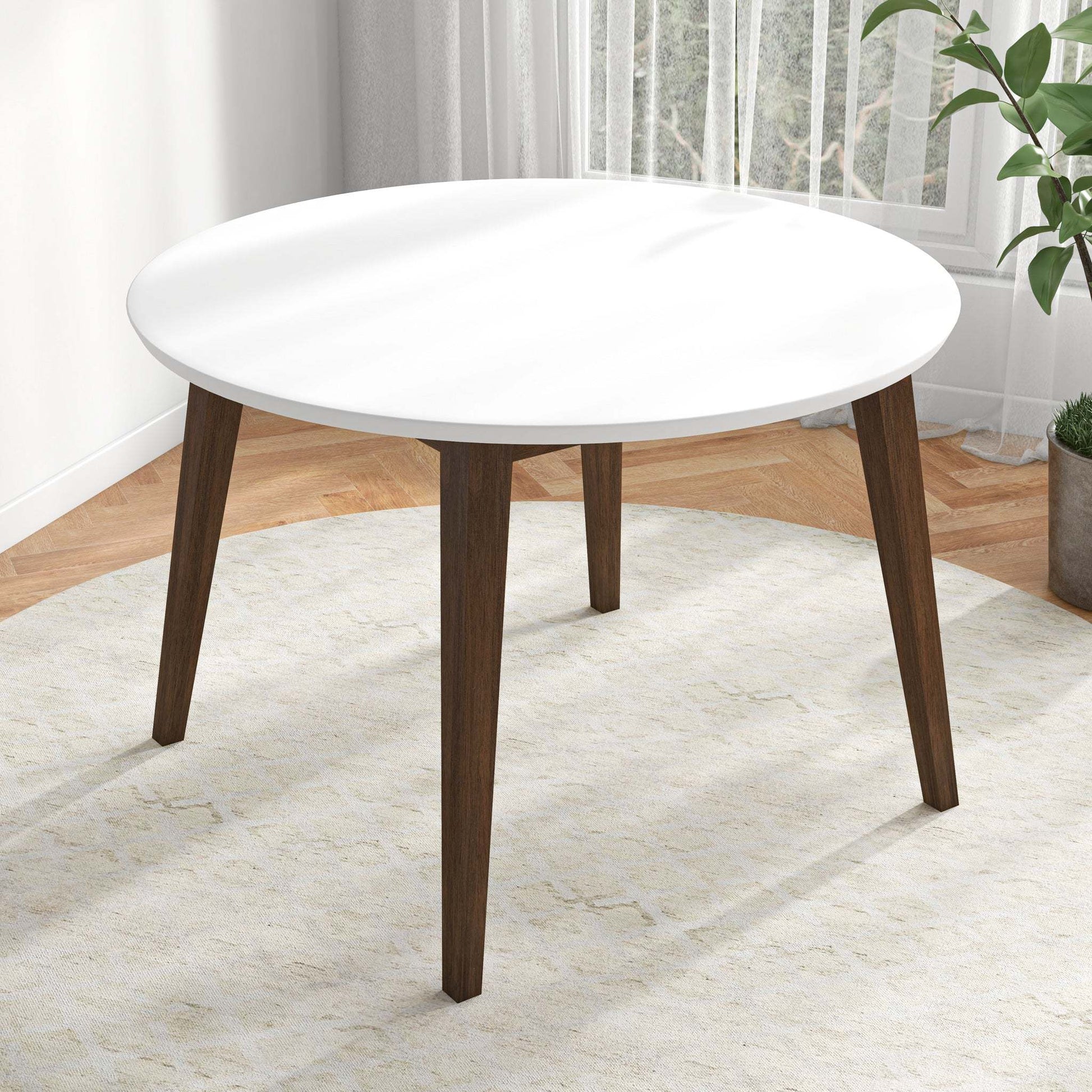 Modern round white dining table with wooden legs in bright living room on rug