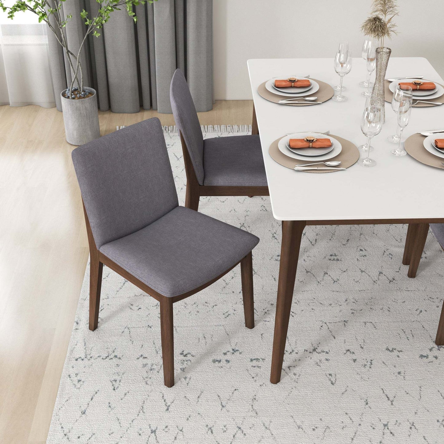 Modern dining room with gray upholstered chairs, white table, and minimalist place settings