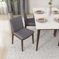 Modern dining room with gray upholstered chairs, white table, and minimalist place settings