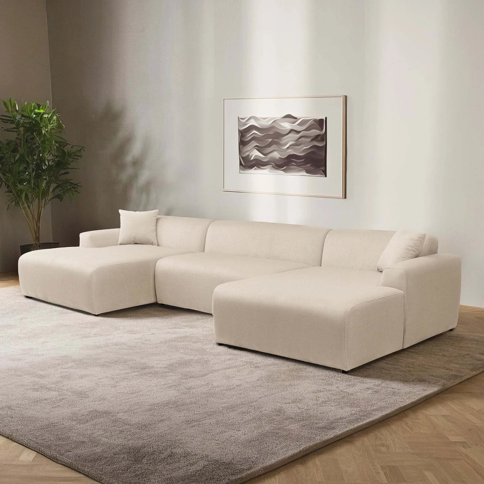 Modern beige sectional sofa in a stylish living room with neutral rug and abstract wall art
