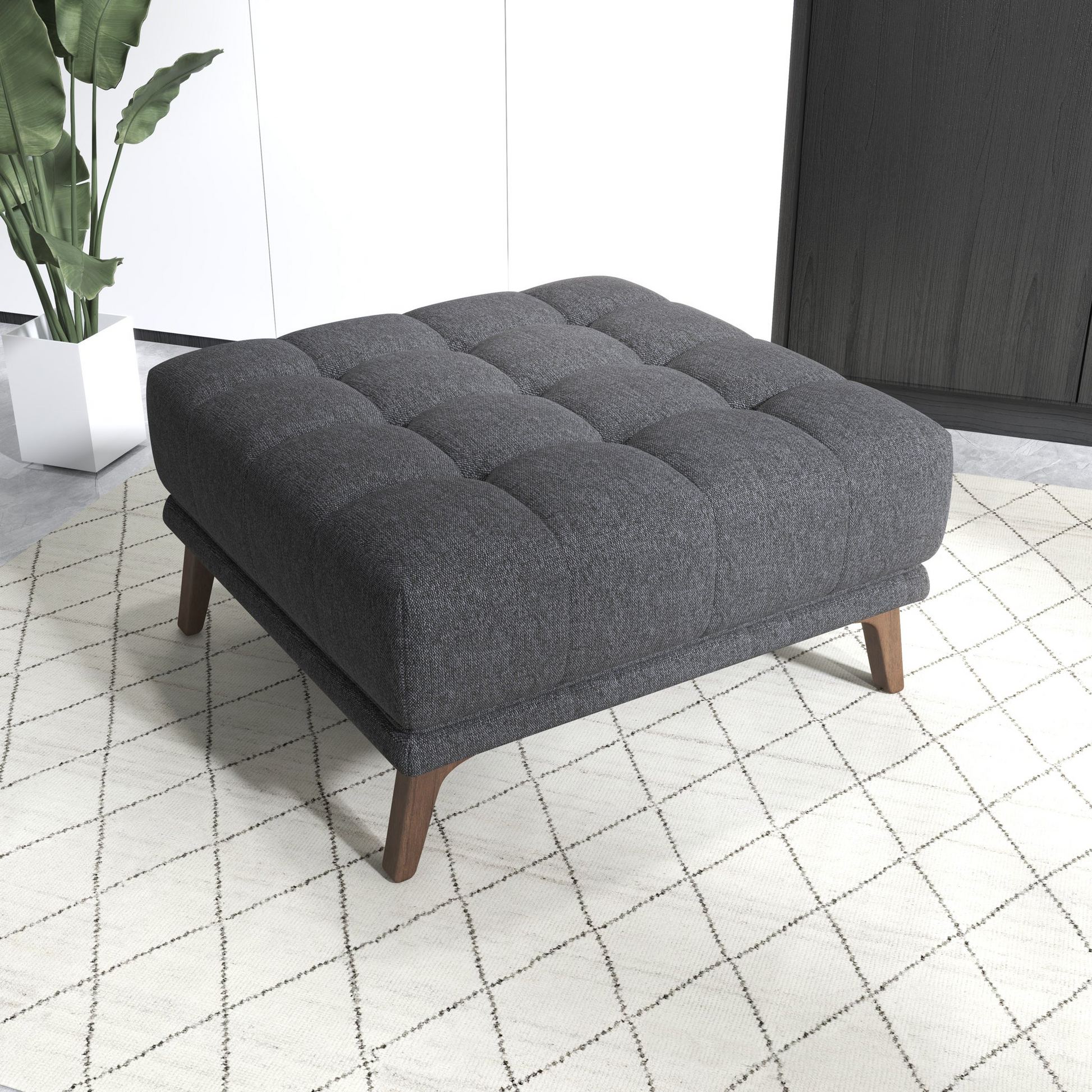 Modern dark gray upholstered ottoman with wooden legs on a patterned rug in a stylish living room