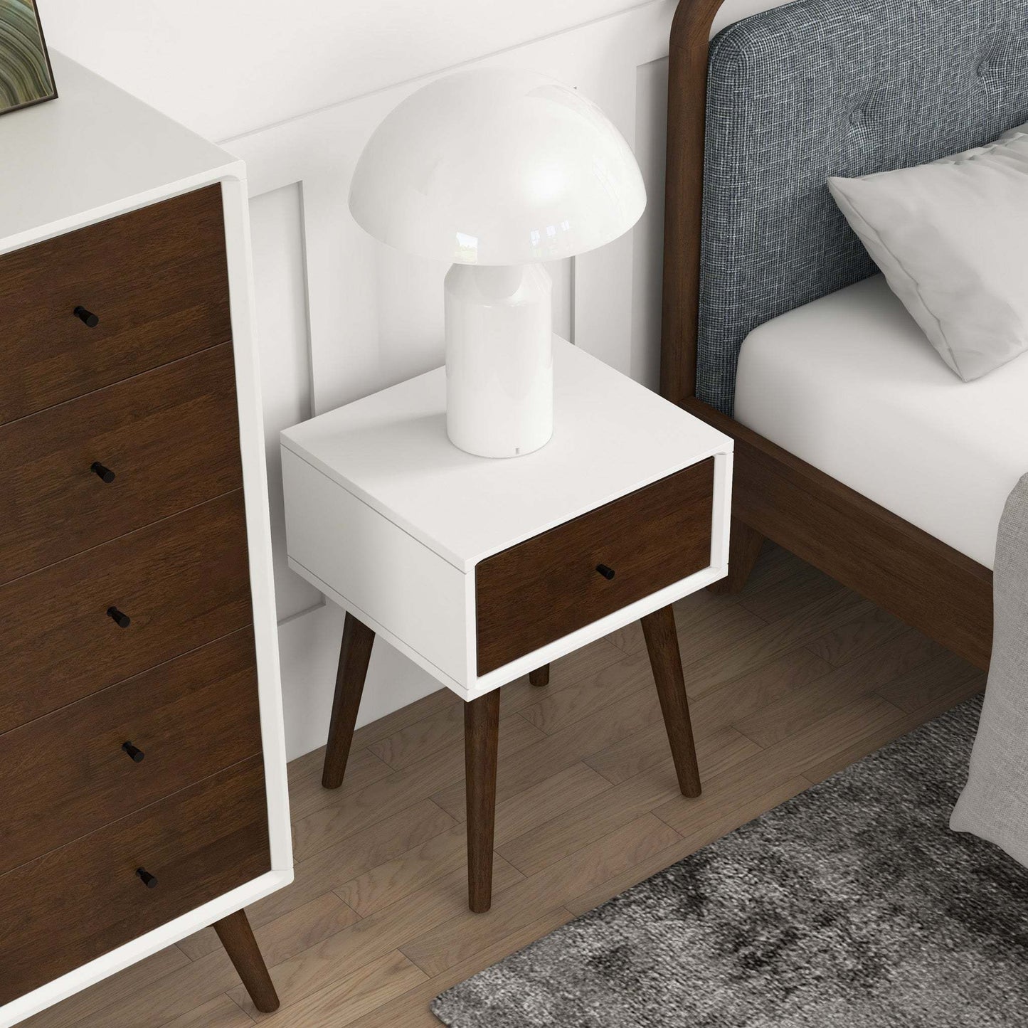 Modern bedroom with white and walnut nightstand, table lamp, dresser, and upholstered bed.