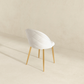 Modern white upholstered chair with gold legs on a beige background, FredCo International furniture
