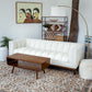 Modern living room with white sofa, wooden coffee table, and decorative shelf from FredCo International