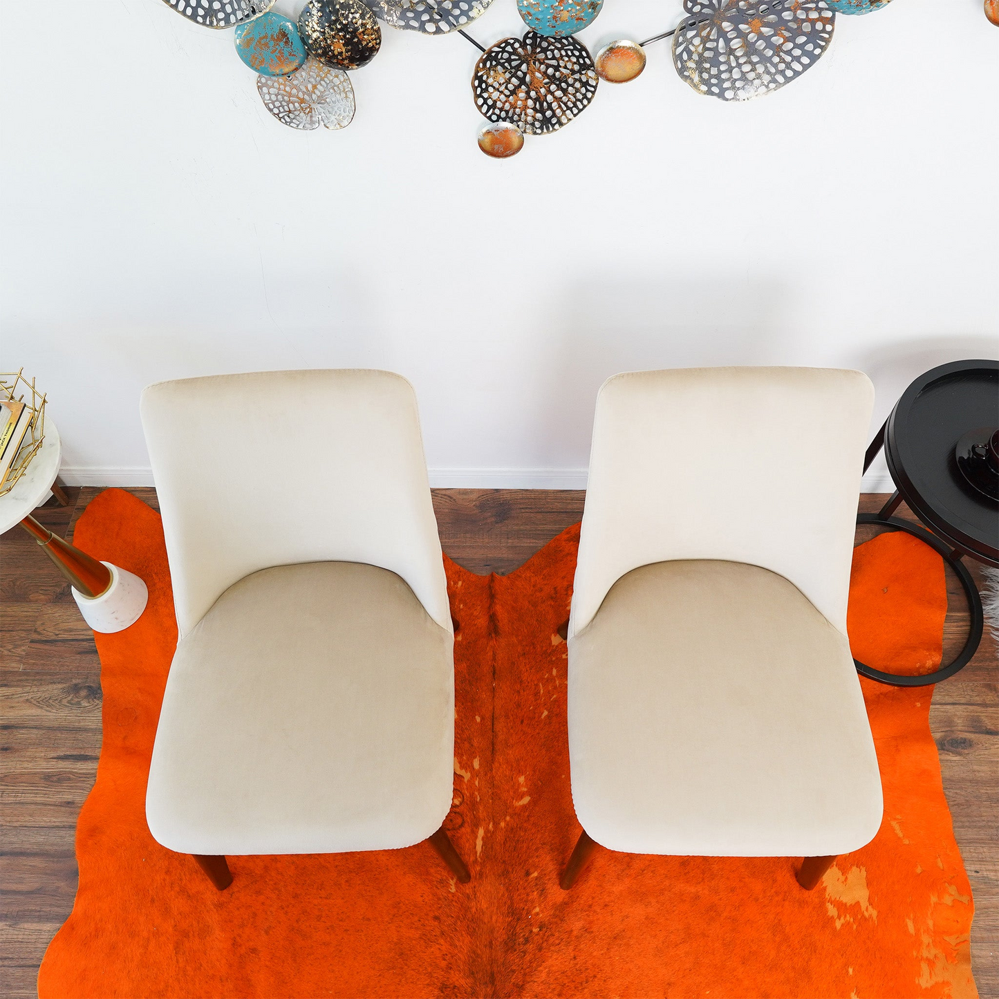 Pair of modern beige chairs on orange rug, wood floor, wall art, furniture from FredCo International