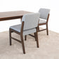 Modern dining room chairs with light gray upholstery and wooden frames next to a wood table