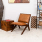 Mid-century modern leather accent chair in stylish living room with wood decor and bookshelf.