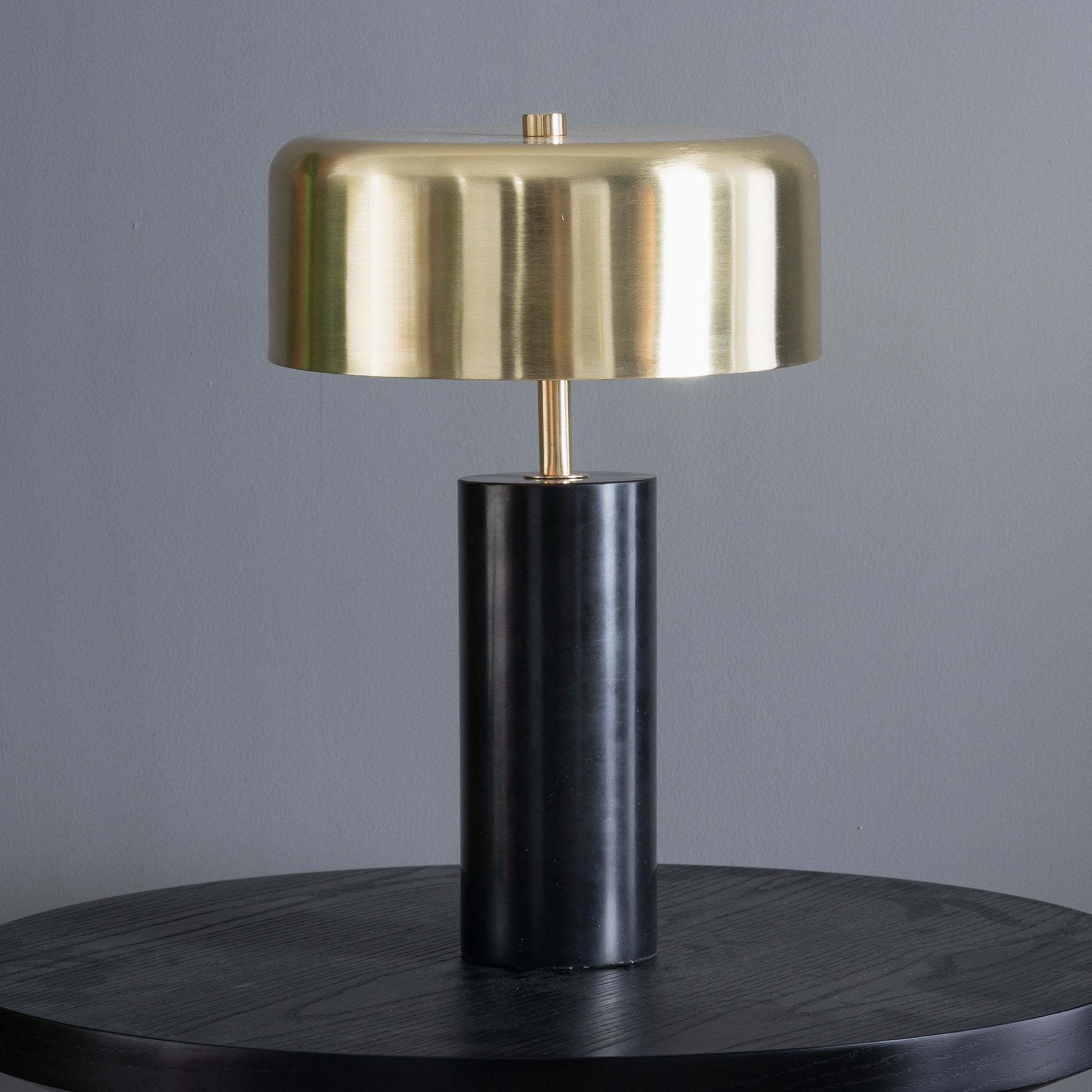 Modern brass and black table lamp on dark wood surface, home decor furniture accent