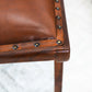 Close-up of brown leather and wood furniture seat with nailhead trim