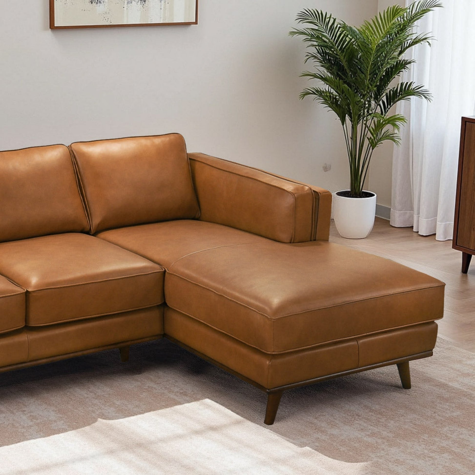 Modern brown leather sectional sofa in living room with potted plant and wall art, FredCo International