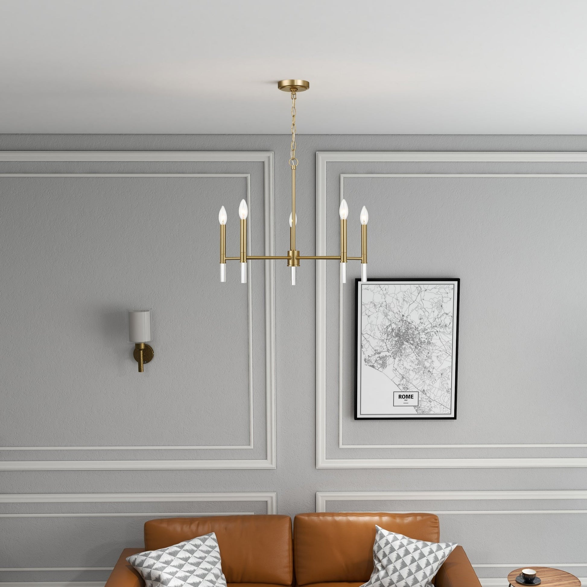 Modern living room with gold chandelier, tan sofa, geometric pillows, and gray paneled walls