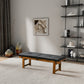 Modern living room with black cushioned wood bench, abstract wall art, and decorative shelves