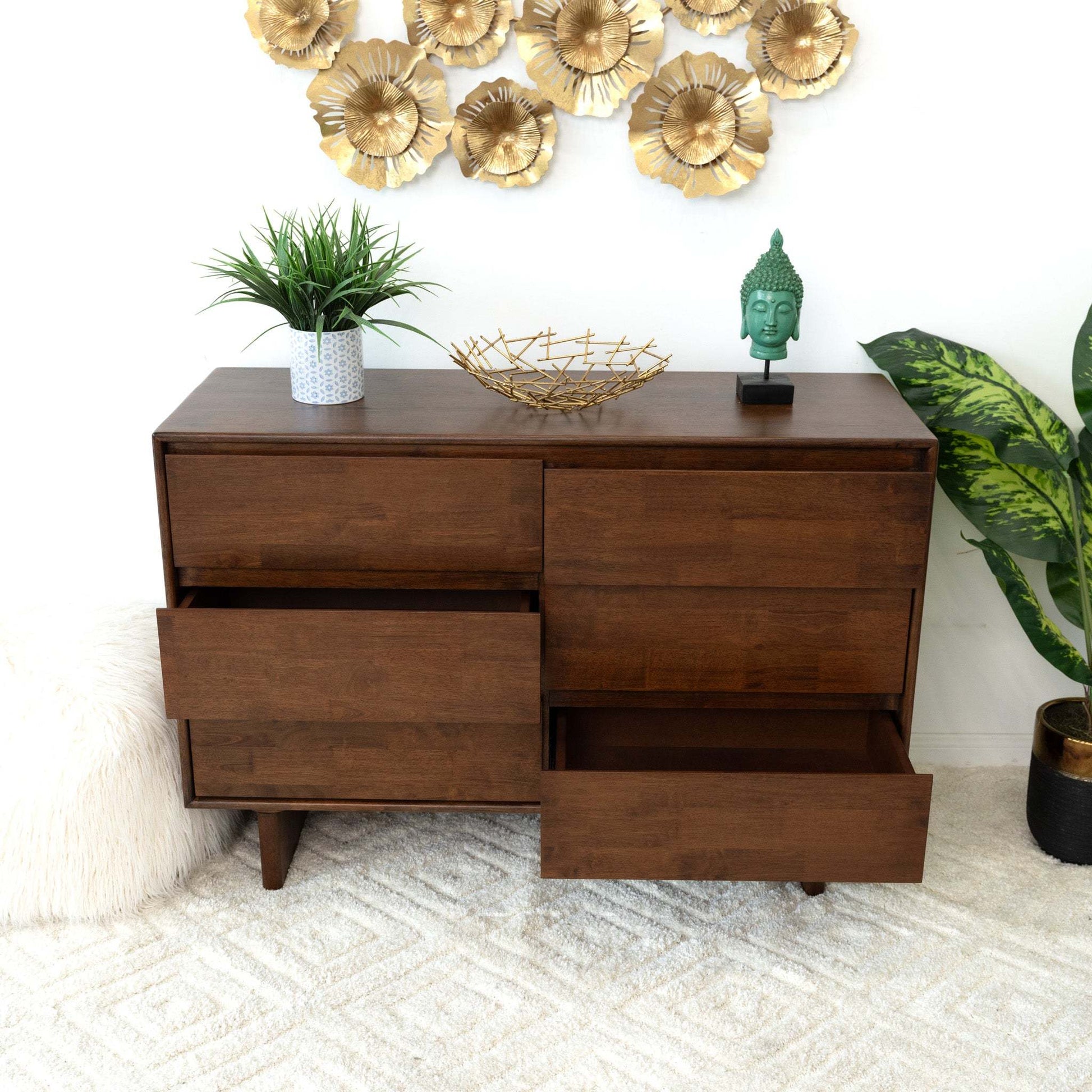 Mid-century modern wood dresser with open drawers, home decor and plants on carpet