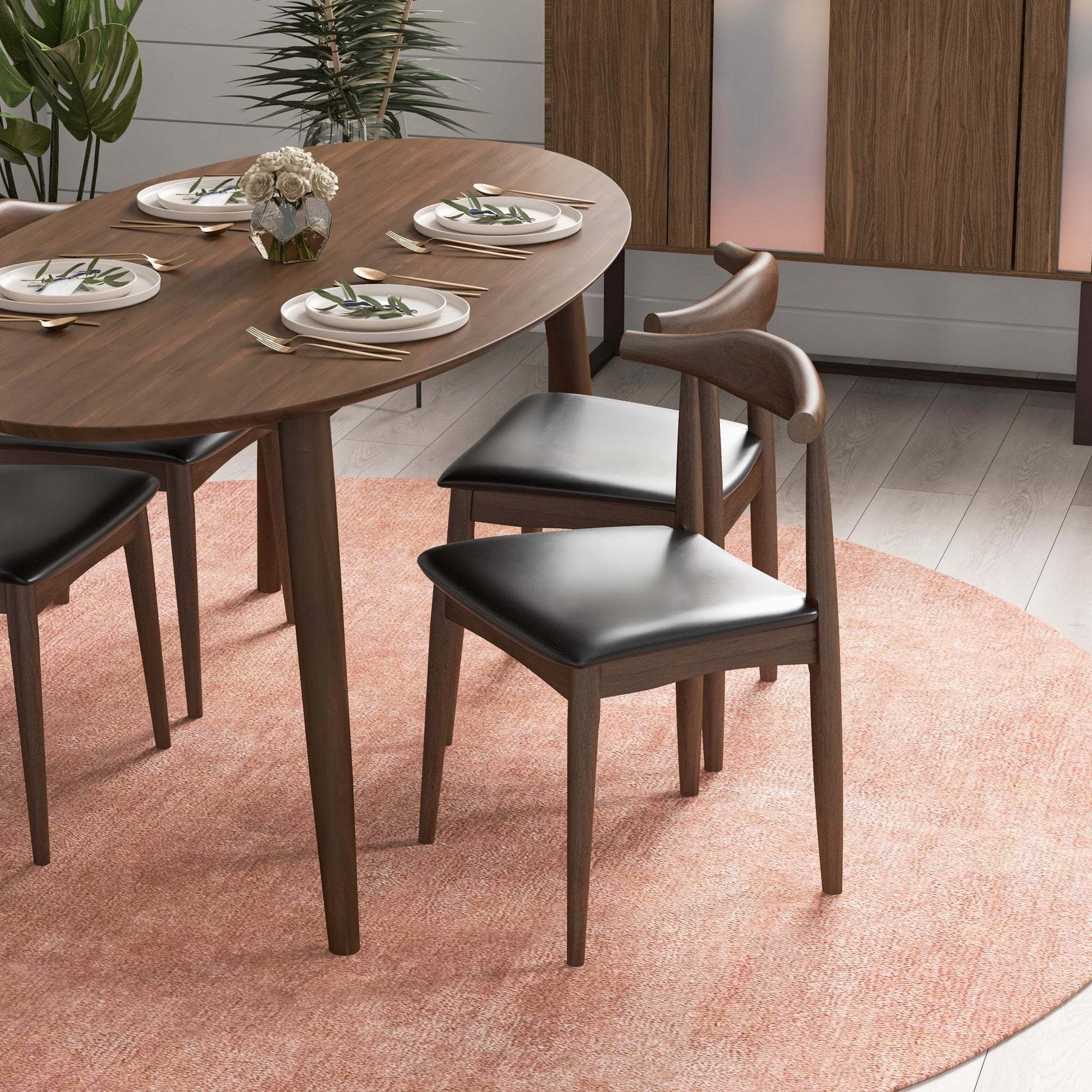 Mid-century modern wood dining table with black chairs on a pink rug, set for four