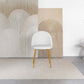 Modern white accent chair with wood legs on a beige rug, abstract wall art background, FredCo furniture
