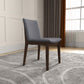 Modern gray upholstered dining chair with dark wood legs on patterned rug in stylish living room
