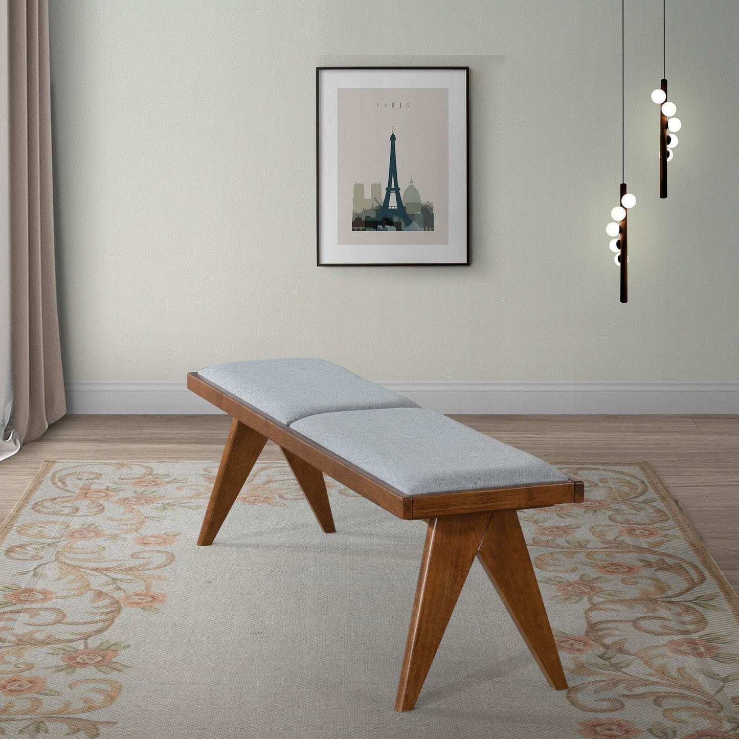 Mid-century modern wood bench with gray cushion on floral rug, wall art, and pendant lights