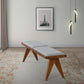 Mid-century modern wood bench with gray cushion on floral rug, wall art, and pendant lights