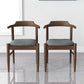 Pair of modern wooden dining chairs with gray fabric seats in bright home interior
