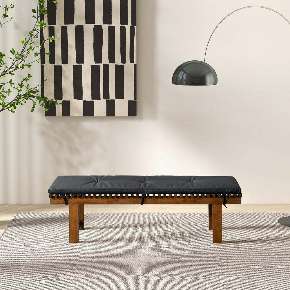 Modern black cushioned bench with wooden legs in stylish living room, abstract art on wall