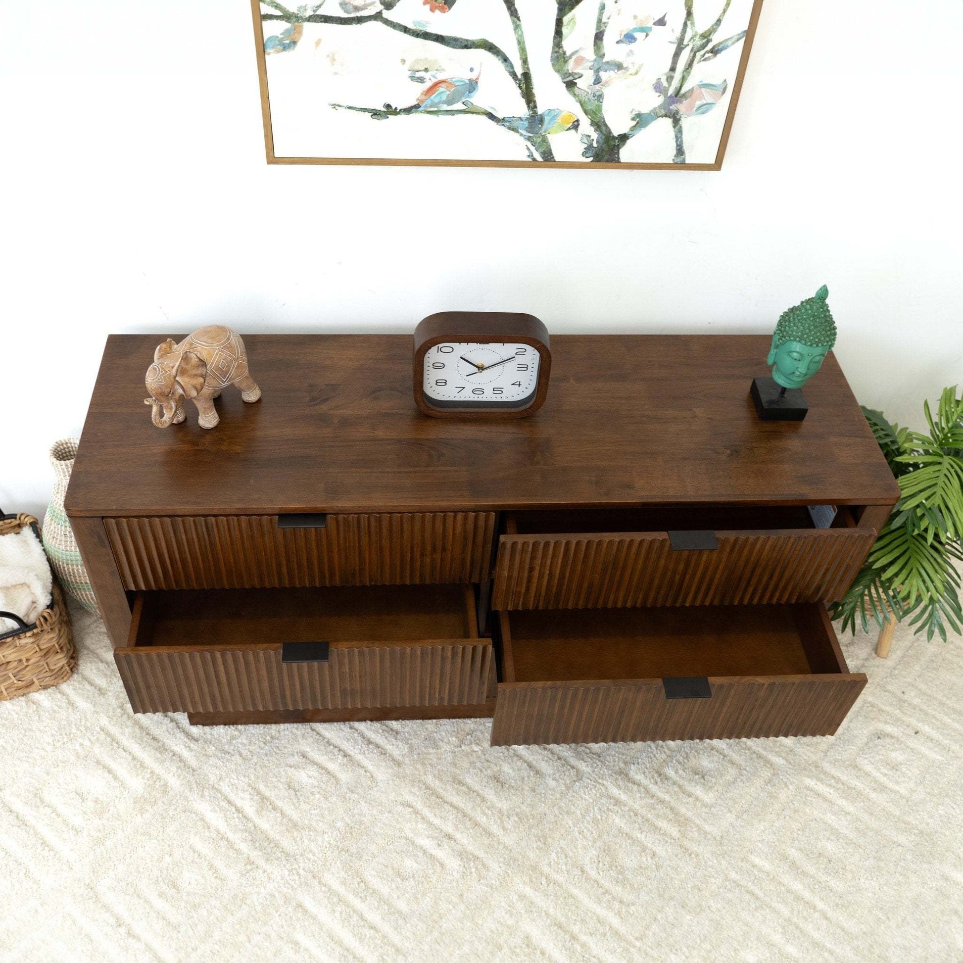 Modern wooden dresser with three open drawers, clock, elephant décor, and green Buddha head on top