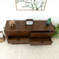 Modern wooden dresser with three open drawers, clock, elephant décor, and green Buddha head on top