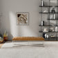 Modern living room with tan upholstered bench, minimalist wall art, and black open shelving