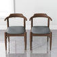 Pair of modern wooden dining chairs with gray cushions in a minimalist room