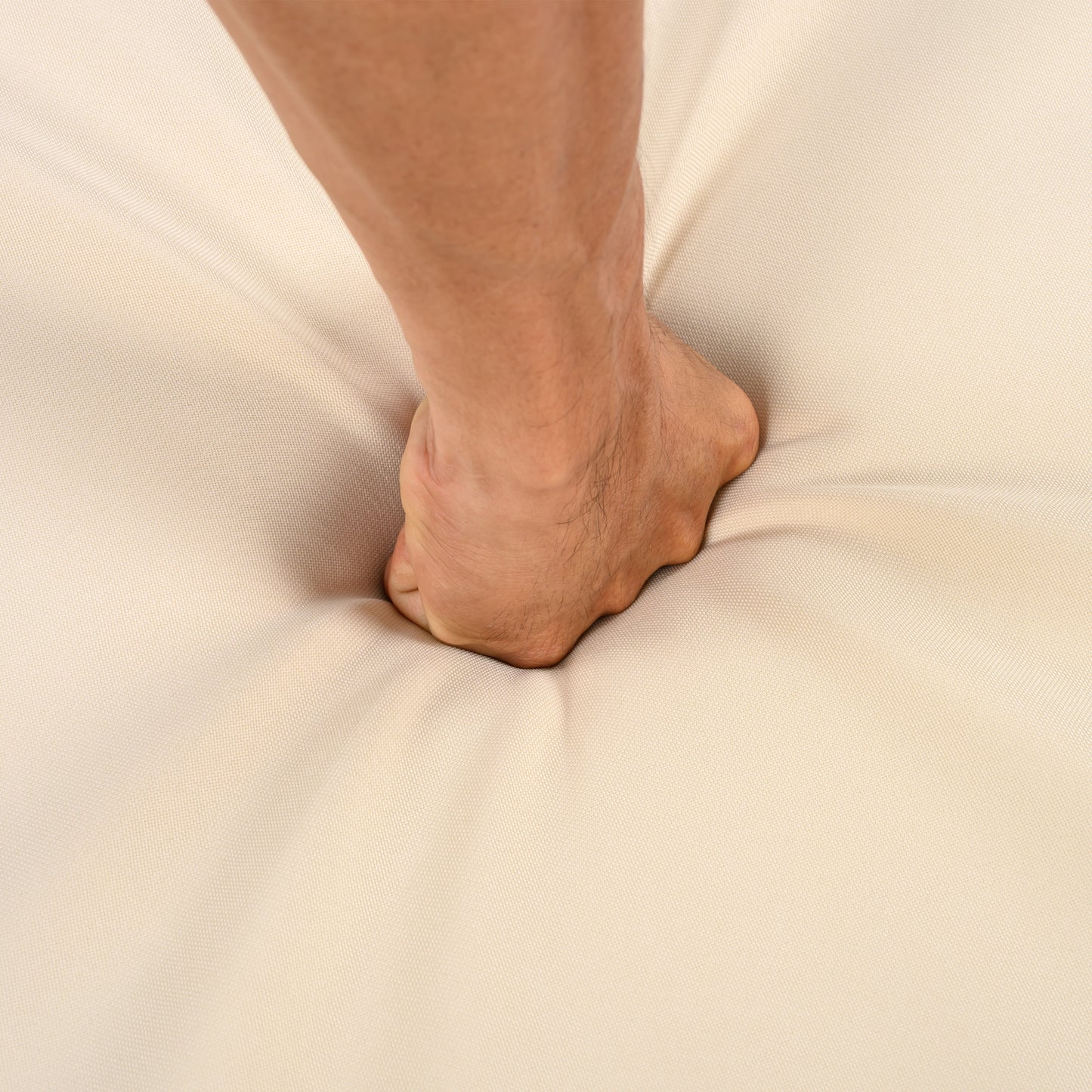Hand pressing into soft beige cushion, testing furniture comfort from FredCo International