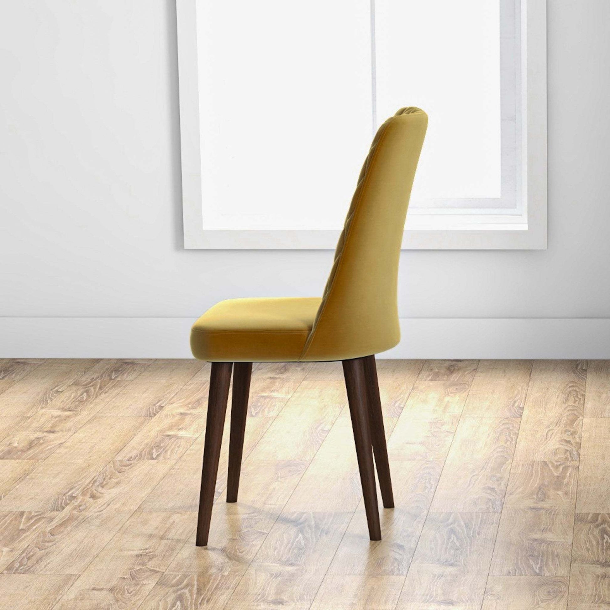 Modern yellow upholstered dining chair with wooden legs in a bright room with wood flooring
