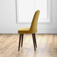 Modern yellow upholstered dining chair with wooden legs in a bright room with wood flooring