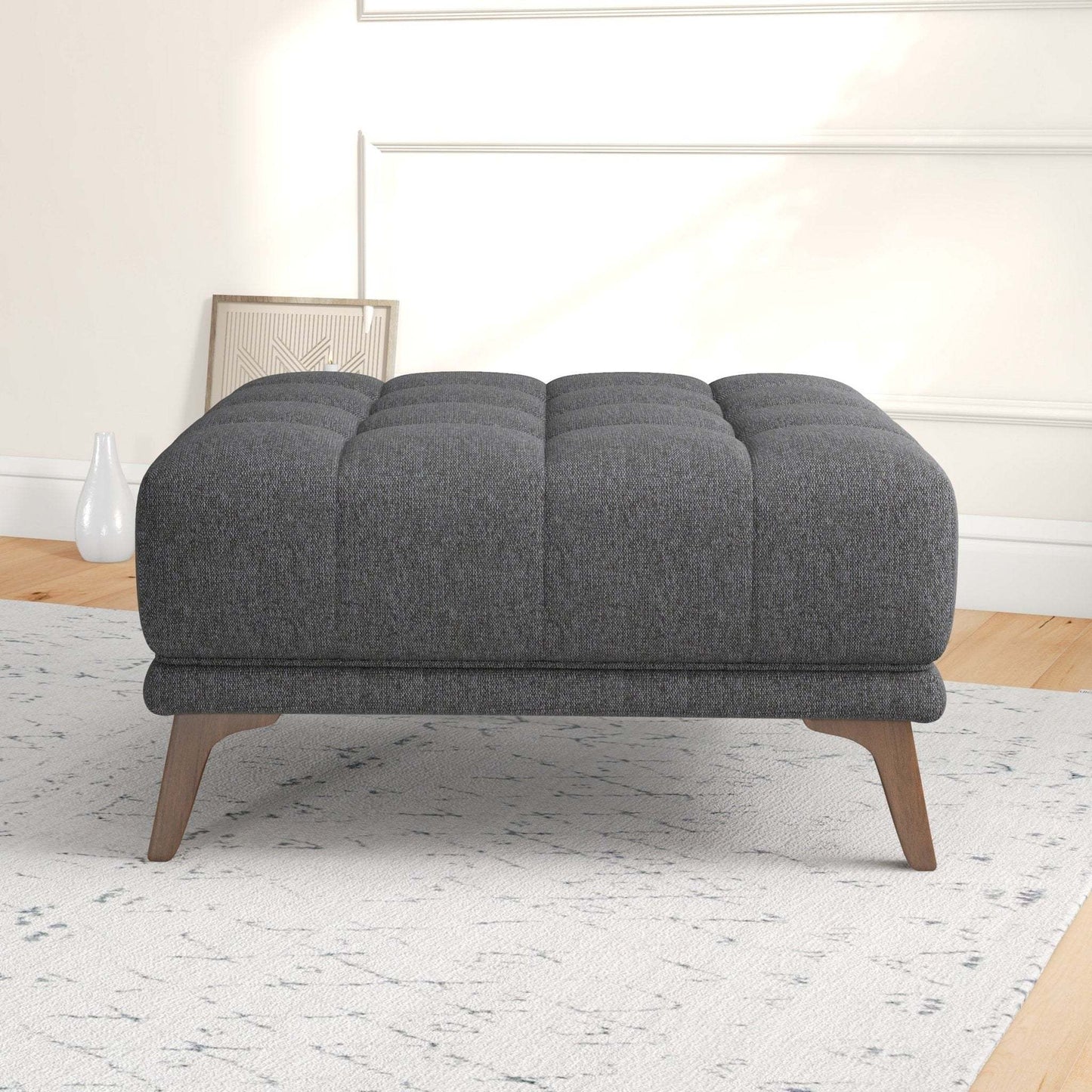 Modern dark gray upholstered ottoman with wooden legs in a stylish living room setting