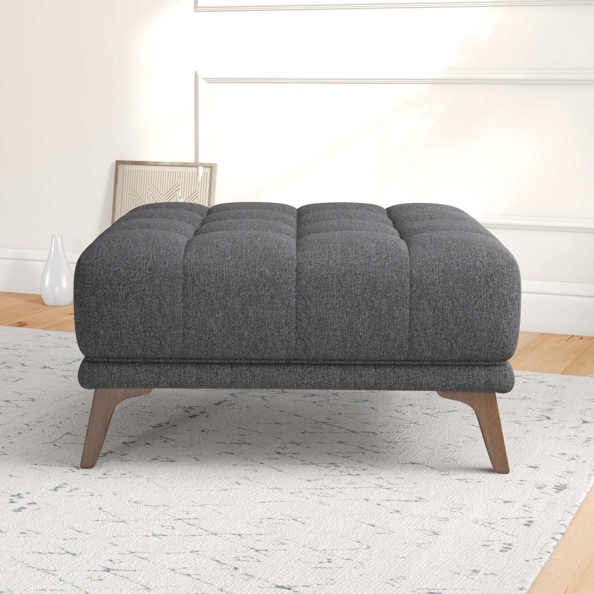 Modern dark gray upholstered ottoman with wooden legs in a stylish living room setting