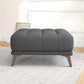 Modern dark gray upholstered ottoman with wooden legs in a stylish living room setting