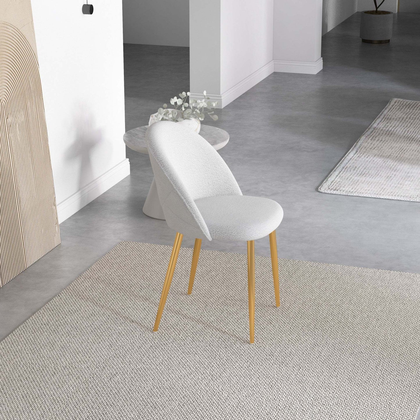 Modern white accent chair with gold legs on a neutral rug in a minimalist living room