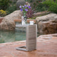 Modern outdoor side table with flowers, coffee maker, and mug by pool on stone patio