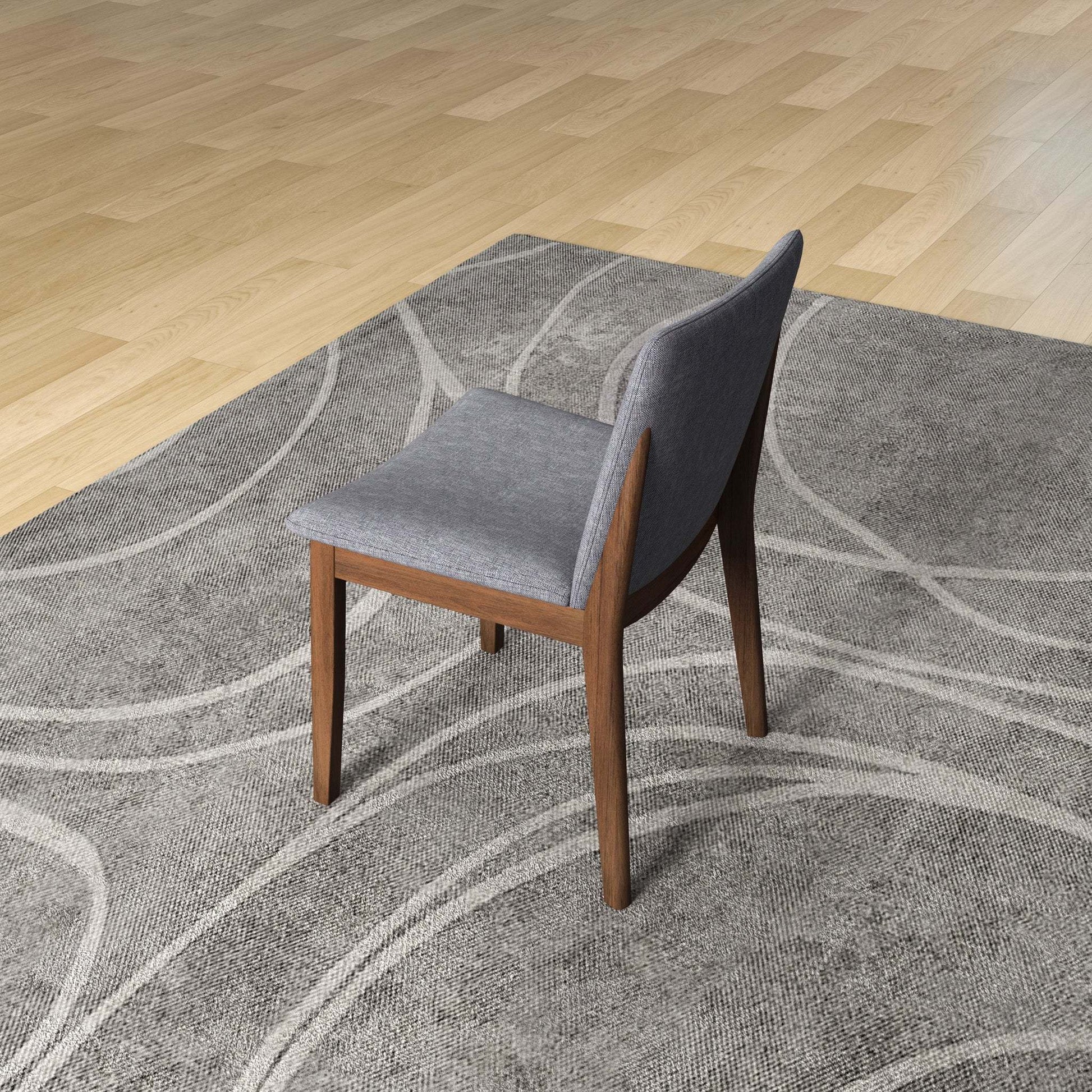 Modern gray upholstered dining chair with wooden legs on patterned rug, hardwood floor background
